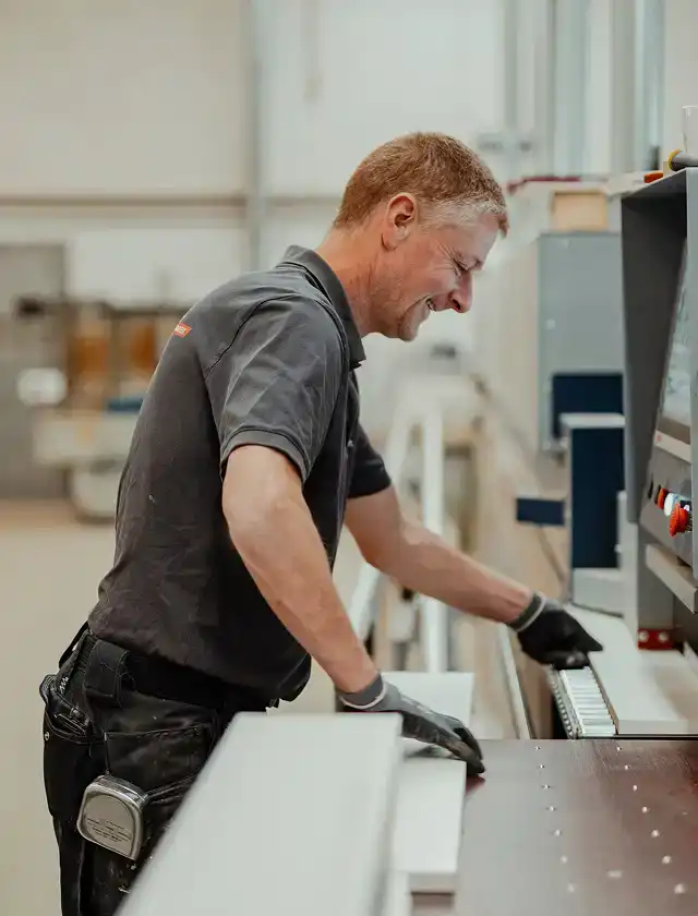 Ein Mitarbeiter bedient eine Maschine in der Werkstatt.