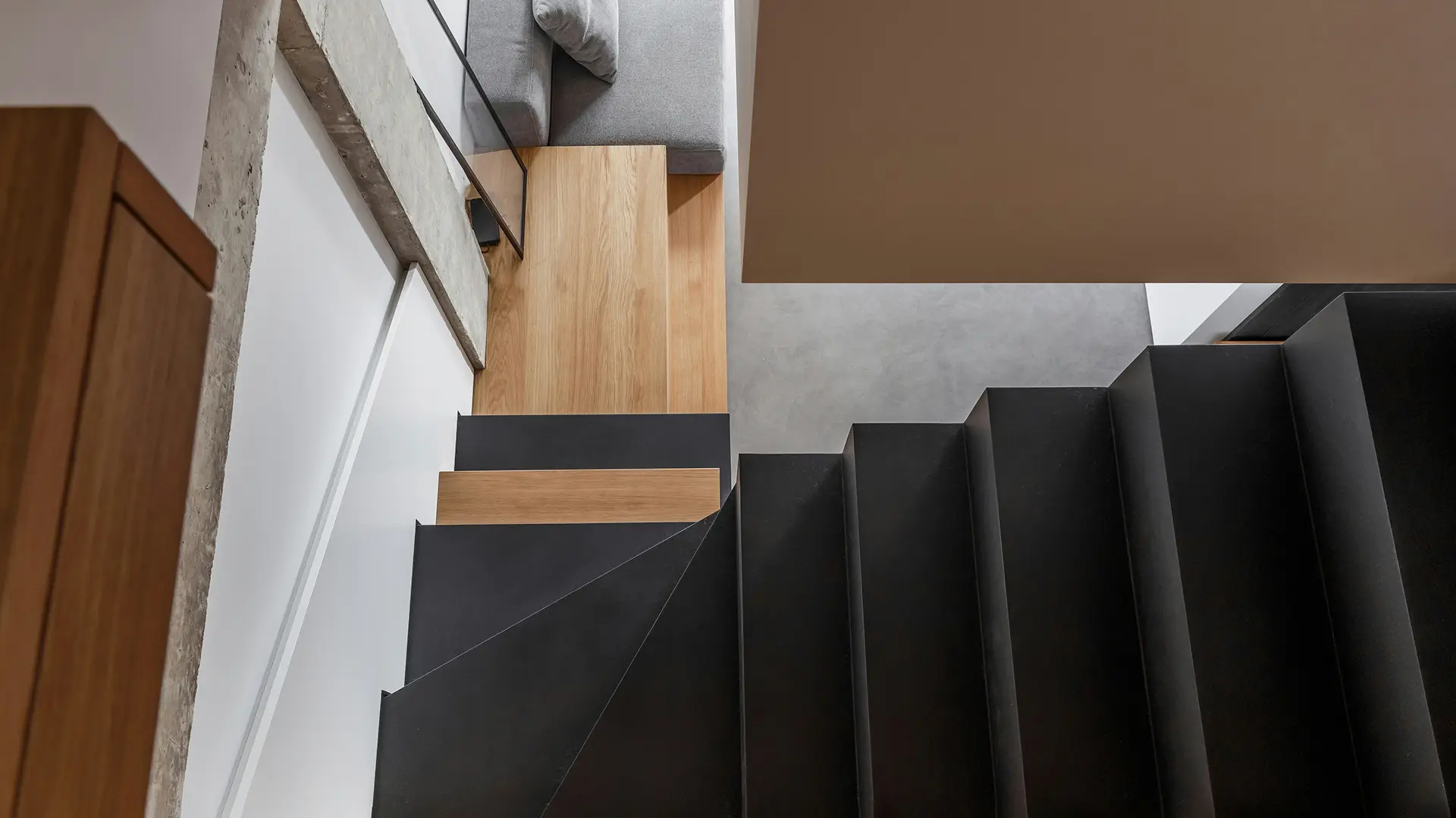 Draufsicht auf eine maßgefertigte schwarze Stahltreppe mit Holzstufen und Podest aus Eiche.