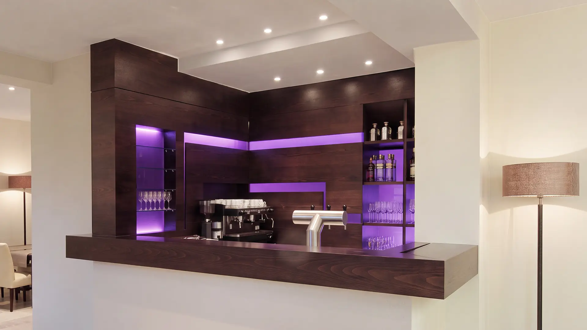 Maßgefertigte Theke mit dunkler Holzverkleidung und violett integrierter LED-Beleuchtung