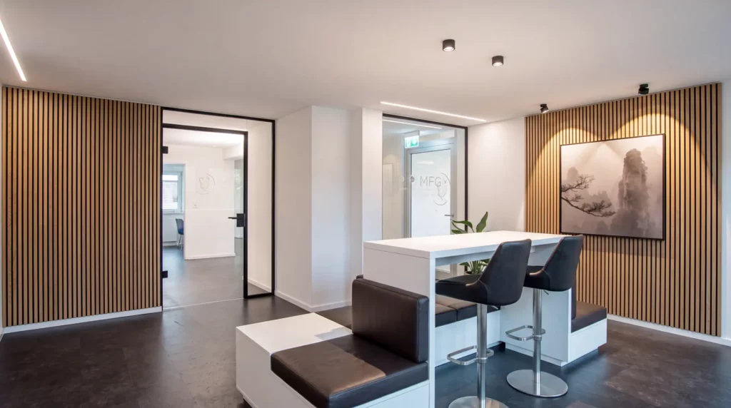 Moderner Wartebereich der MKG-Praxisklinik mit maßgefertigten Sitzmöbeln, Hochtisch und Holzlamellen